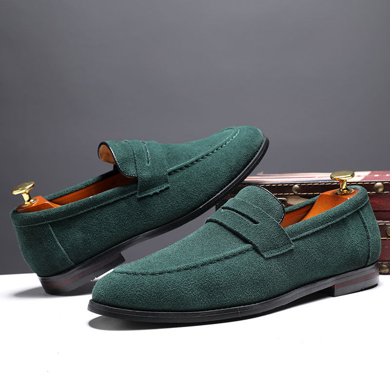 Green suede men's loafers with leather lining and wooden shoe trees on white surface