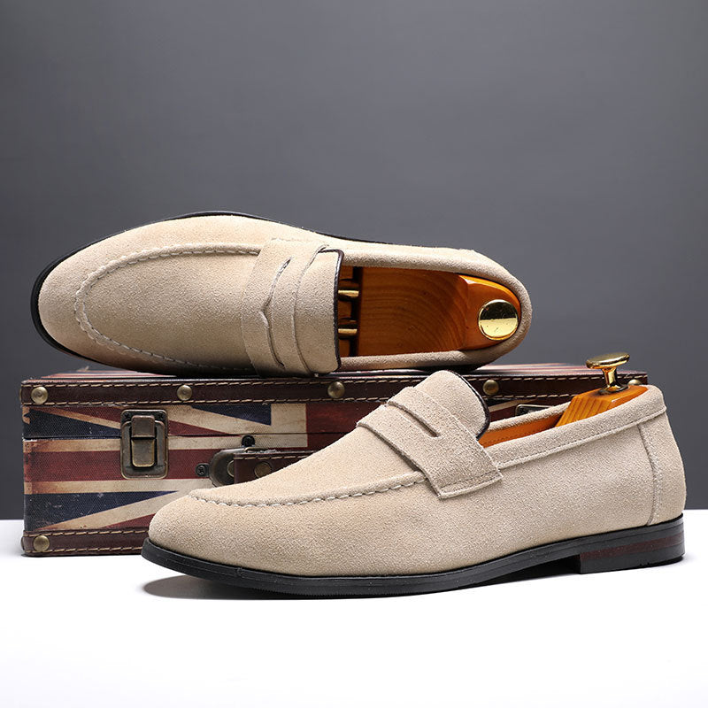 Beige suede men's loafers with wooden shoe trees displayed on a vintage Union Jack suitcase
