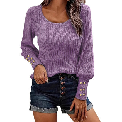Woman wearing lilac ribbed long sleeve sweater with round neck and button details, paired with dark denim shorts