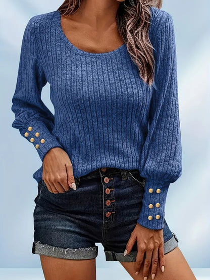 Woman in blue ribbed long-sleeve sweater with gold buttons on cuffs paired with dark denim shorts