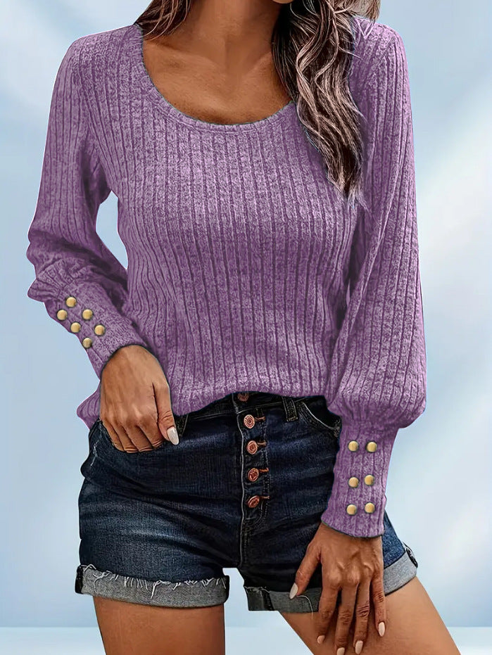 Woman wearing purple ribbed long sleeve sweater with gold buttons and dark denim shorts