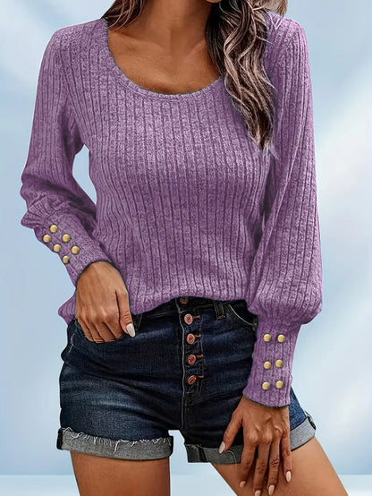 Woman wearing purple ribbed long sleeve sweater with gold buttons and dark denim shorts