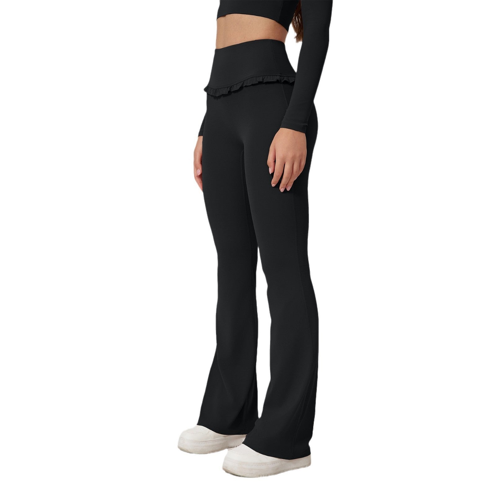 Woman wearing black high-waist ruffled yoga pants and black long-sleeve top with white sneakers