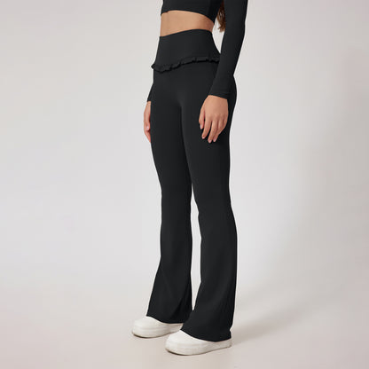 Woman wearing black high-waist flared yoga pants with ruffle detail and white sneakers