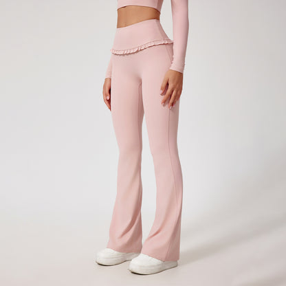 Woman wearing pale pink high-waist flared yoga pants with ruffled waistband and white sneakers