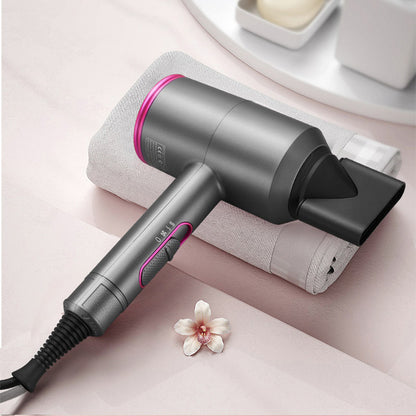 Gray and pink ionic hair dryer with concentrator nozzle on white towel with flower on pink surface