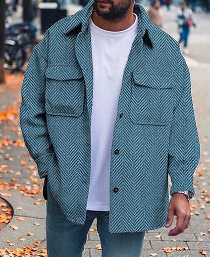 Men's blue herringbone pattern polo collar coat with long sleeves, worn over white shirt outdoors
