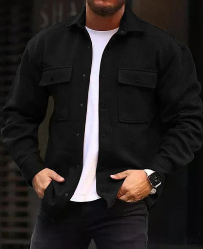 Man wearing black long-sleeve polo collar coat with front pockets over white t-shirt, casual fall outerwear