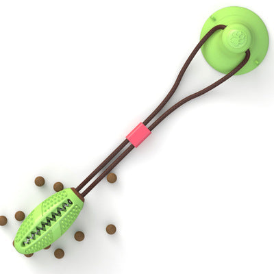 Green dog chew toy with suction cup and brown tug rope, surrounded by dog kibble