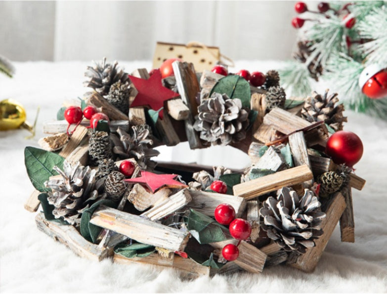 Rustic Christmas wreath with pine cones, red berries, red stars, green leaves, and wooden sticks on white surface