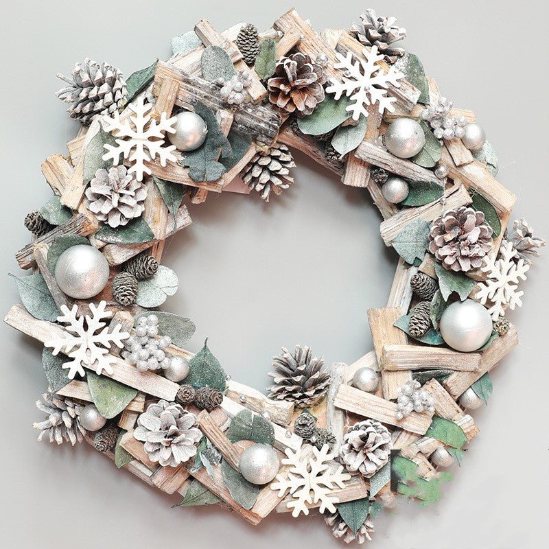 Silver Christmas wreath decorated with pine cones, white snowflakes, silver baubles, and green leaves