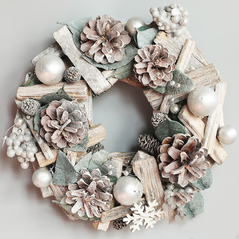 Silver Christmas wreath with frosted pinecones, silver ornaments, green leaves, wood sticks, and white snowflake