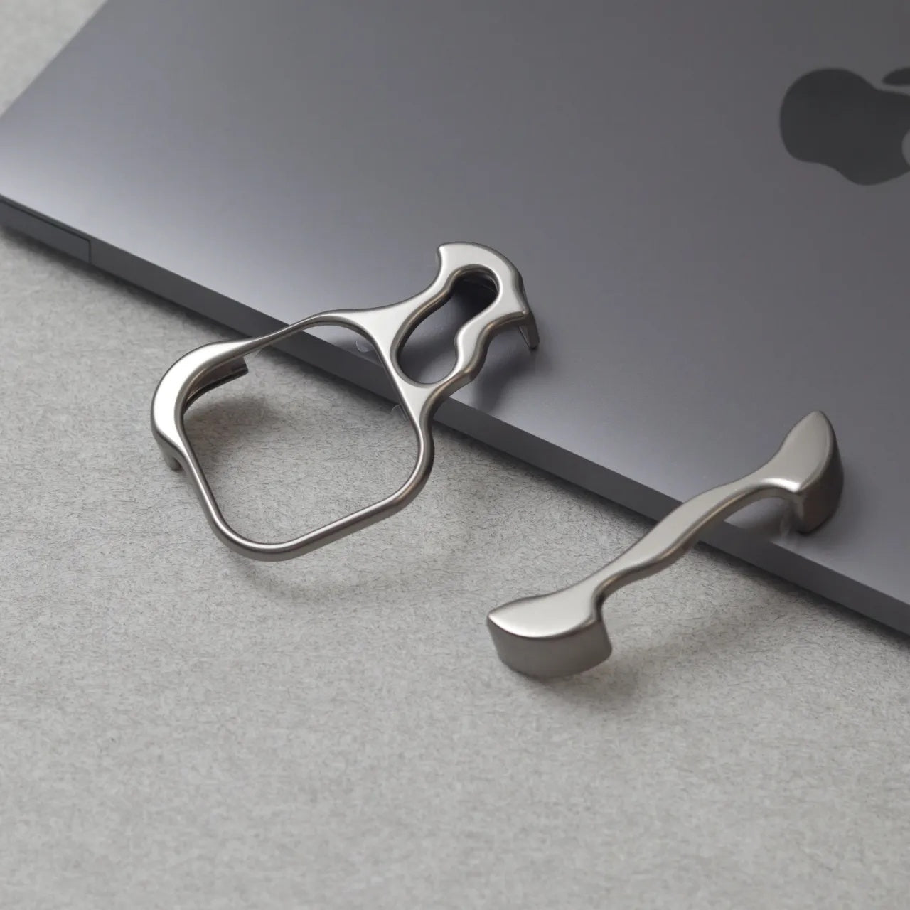 Zinc alloy metal phone holder and stand attached to the edge of a gray Apple MacBook laptop
