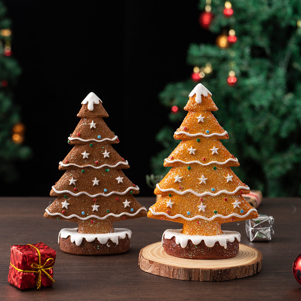 Two festive ginger cake Christmas tree decorations with icing and colorful sprinkles on wooden surface