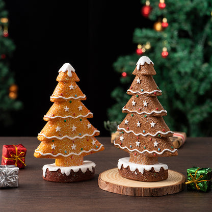 Two gingerbread Christmas tree decorations with white icing and colorful star sprinkles on a wooden table