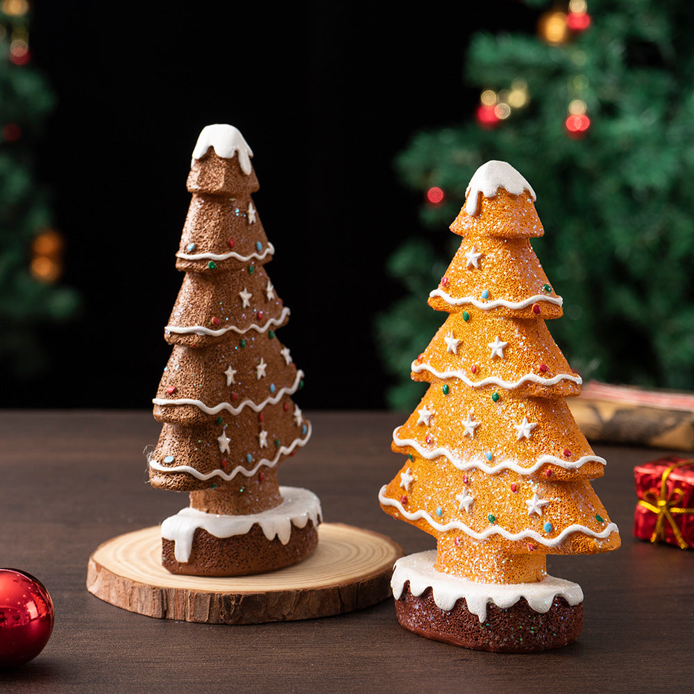 Two glittery gingerbread Christmas tree decorations with white icing and colorful ornaments on wooden and table surfaces