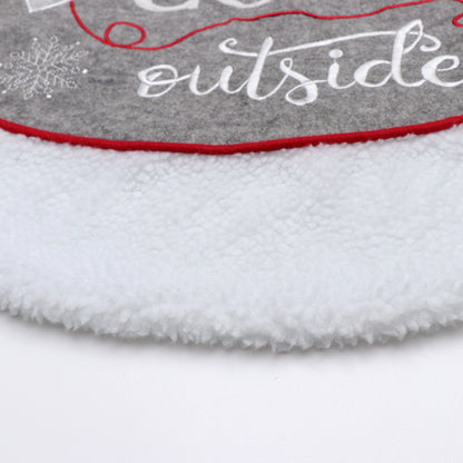 Close-up of gray Christmas tree skirt with white fleece border and red trim featuring snowflake and text design