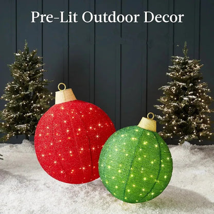 Pre-lit outdoor Christmas decor featuring large red and green glowing round lantern ornaments on snowy ground with decorated evergreen trees