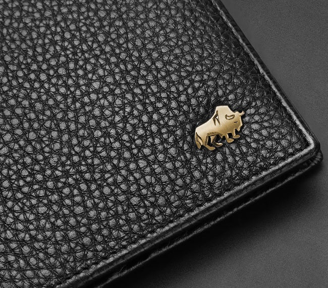 Close-up of black textured leather wallet with gold American bison emblem on corner