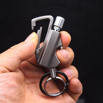 Hand holding a gray metal keychain lighter with carabiner clip and key ring on black background
