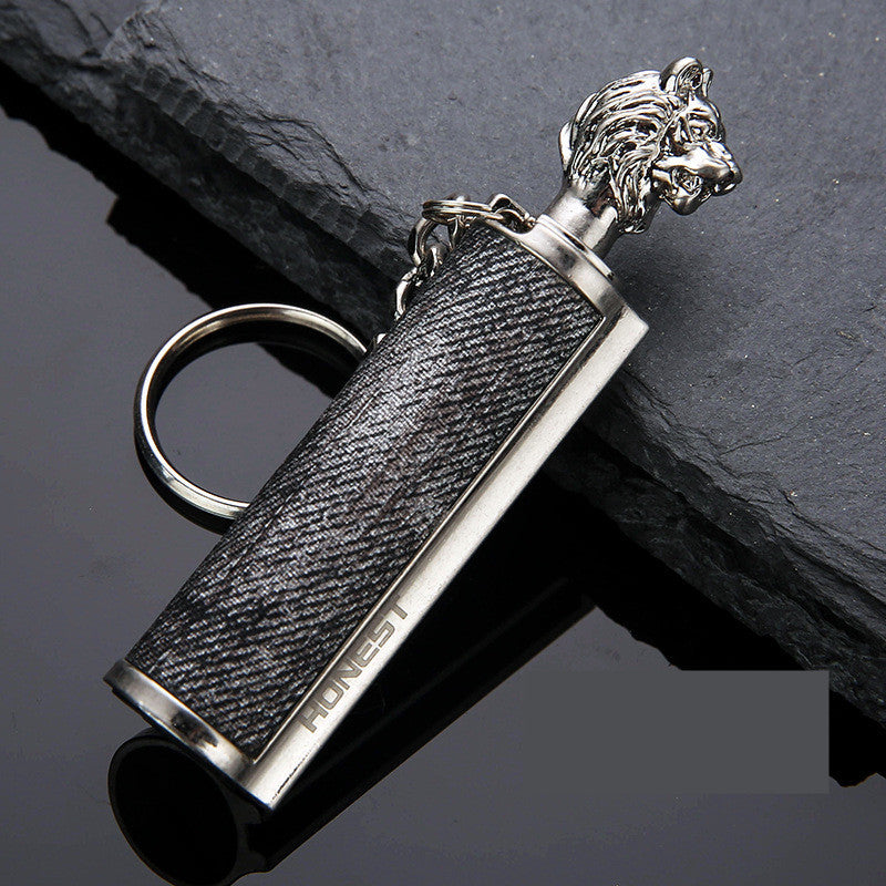 silver keychain with lion head cap and black textured body on black surface