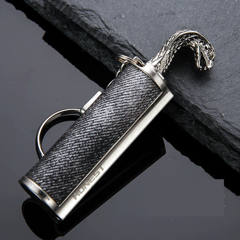 Stylish black and silver metal keychain lighter with snake head design and HONEST logo on dark slate surface