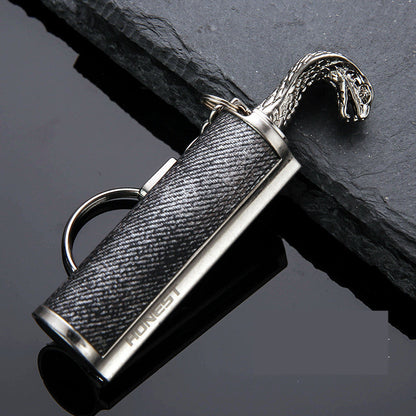 Stylish black and silver metal keychain lighter with snake head design and HONEST logo on dark slate surface