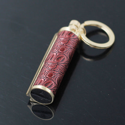 gold metal keychain lighter with red textured grip and black base on black surface
