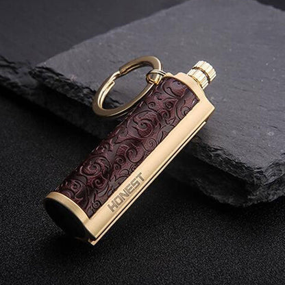 Golden metal keychain lighter with embossed dark brown leather and HONEST engraving on black surface
