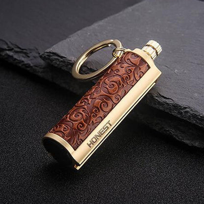 Gold metal keychain lighter with embossed brown leather grip and HONEST branding on black surface