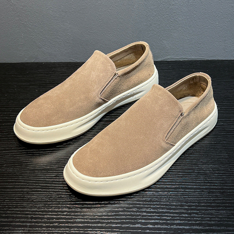 Beige suede men's casual slip-on shoes with thick white soles on black wooden surface