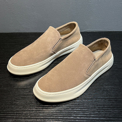 Beige suede men's casual slip-on shoes with thick white soles on black wooden surface