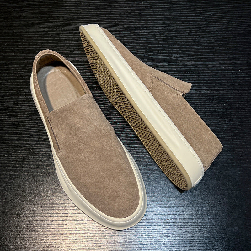 Men's casual slip-on shoes in light brown suede with white rubber soles on black wood surface