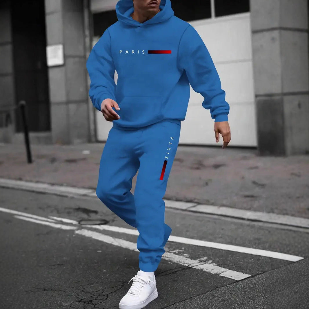 Man wearing blue Paris printed hooded tracksuit and white sneakers walking on city street