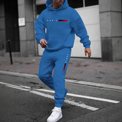 Man wearing blue Paris printed hooded tracksuit and white sneakers walking on city street
