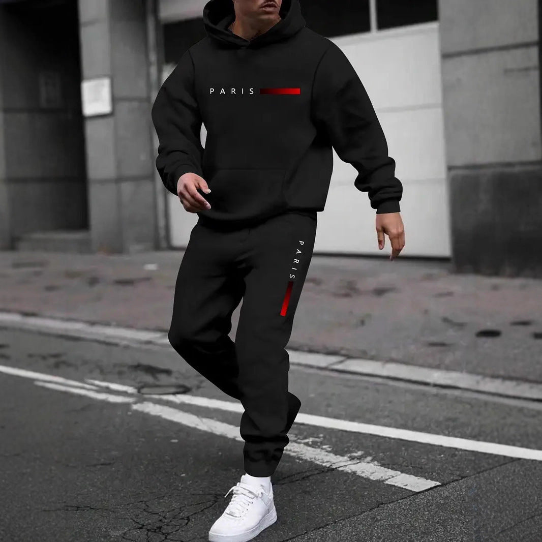 Man wearing black Paris printed hoodie and jogger tracksuit with white sneakers on city street