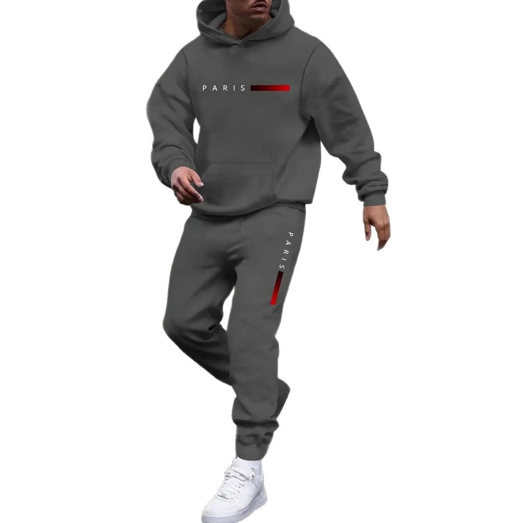 Man wearing gray men's tracksuit set with hooded sweatshirt and joggers featuring Paris text and red accents