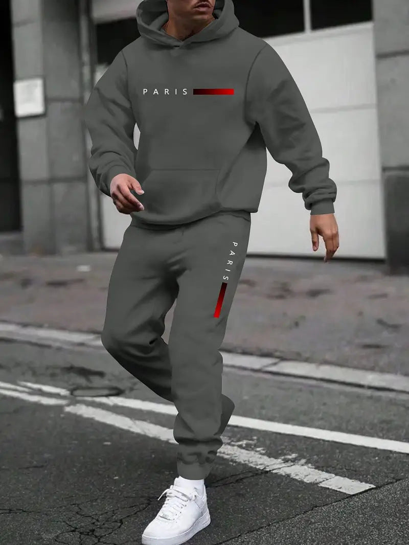 man wearing gray hooded tracksuit with red PARIS text walking on city street, white sneakers
