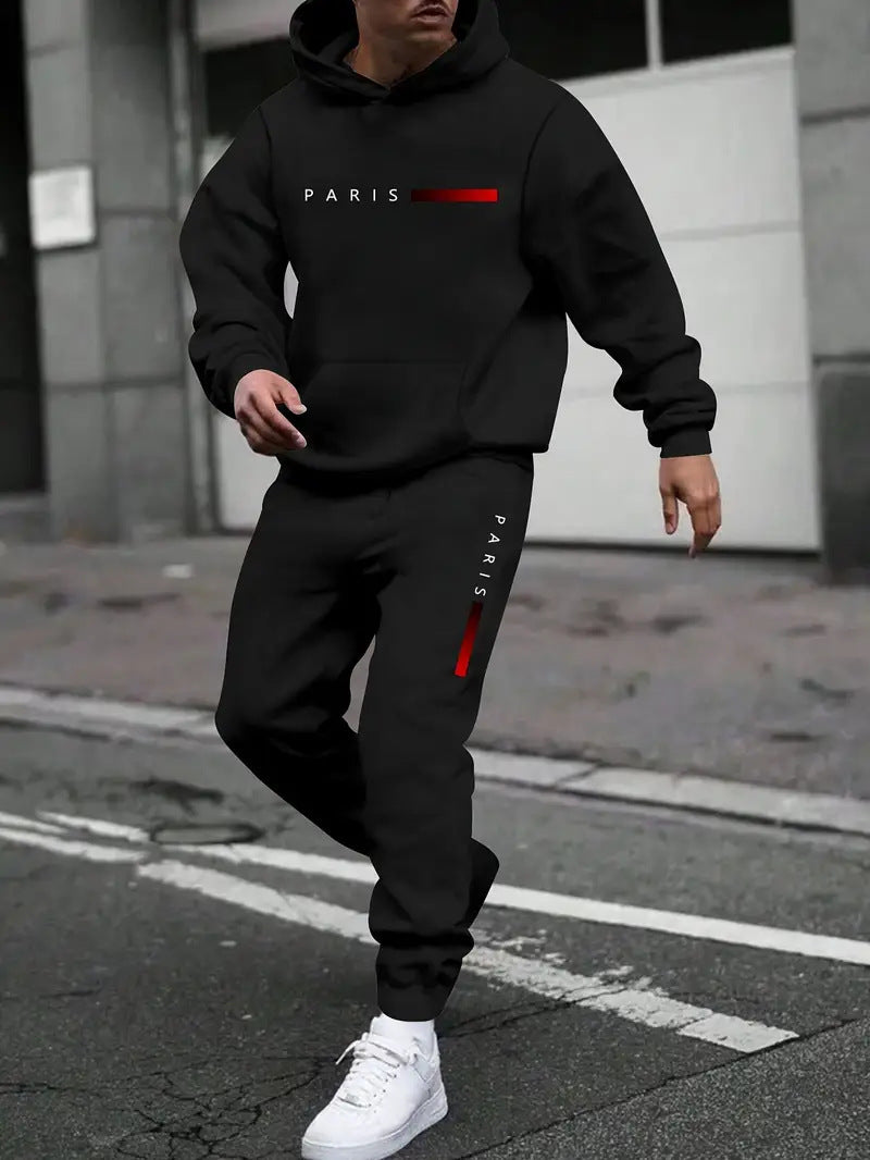 Man wearing black Paris hoodie and matching joggers with red stripe, white sneakers on city street