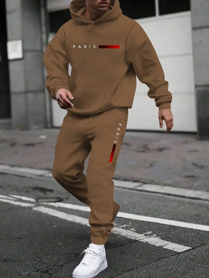 Man wearing brown hooded tracksuit set with PARIS logo in urban street setting, paired with white sneakers