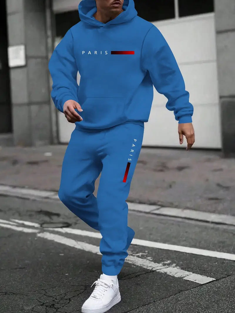 Man wearing blue hooded tracksuit set with PARIS text and red stripe, white sneakers, urban street background