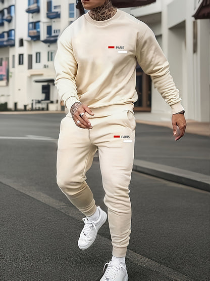 Man wearing beige Paris logo tracksuit with sweatshirt and joggers on city street, white sneakers