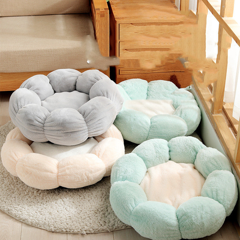 Soft plush flower-shaped pet beds in pastel gray, beige, and green on a wooden floor near furniture