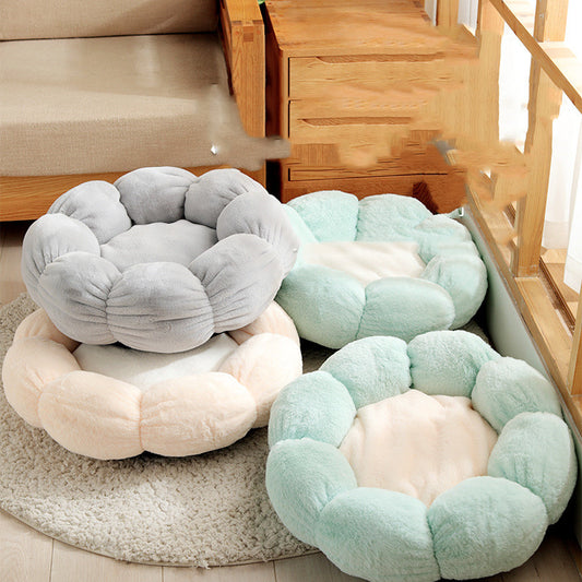 Soft plush flower-shaped pet beds in pastel gray, beige, and green on a wooden floor near furniture