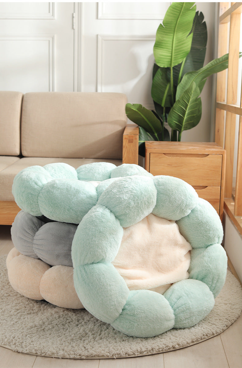 soft plush pet beds in pastel colors stacked in cozy living room setting with beige sofa and green plant