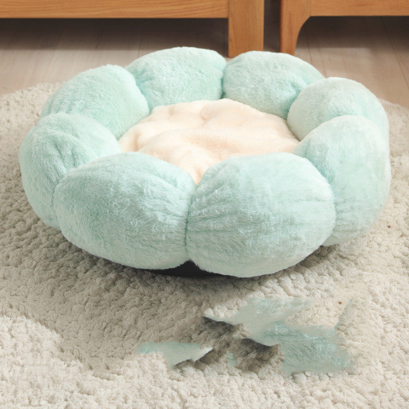 Soft green flower-shaped pet bed with light beige center on a textured cream rug
