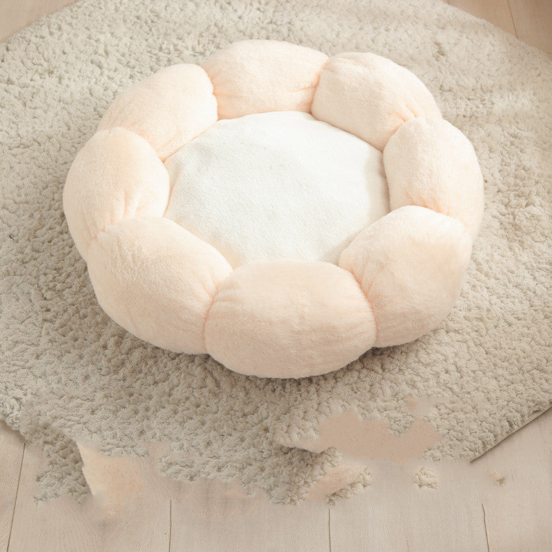 Plush flower-shaped pet bed with soft pale pink petals and white center on beige shaggy rug