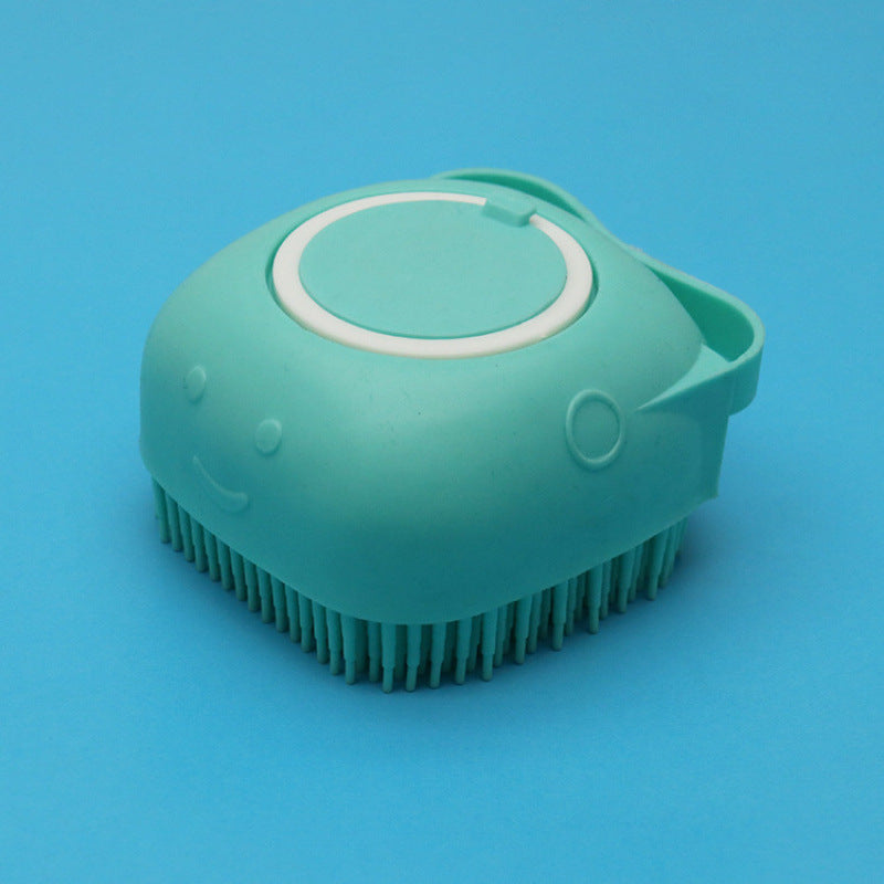 Mint green silicone dog bath brush with soft bristles and smiley face on blue background