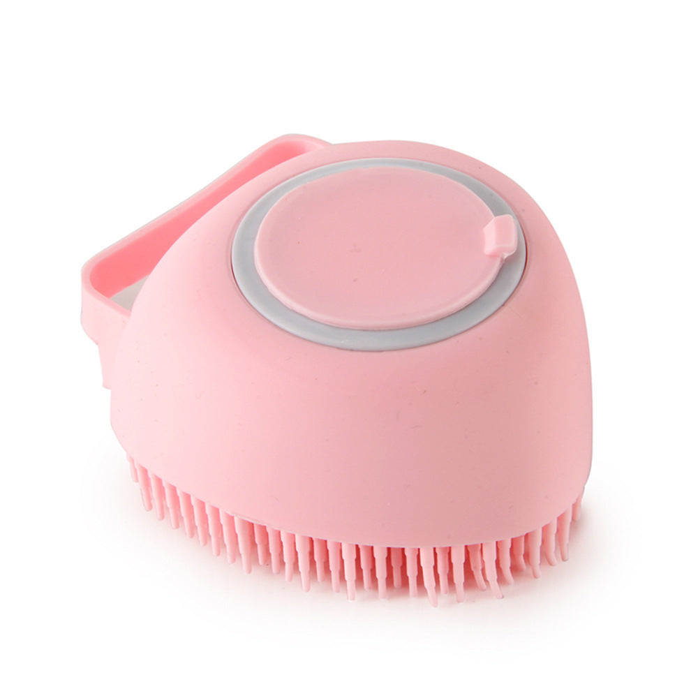 Pink silicone pet grooming brush with soft bristles and a round top button dispenser