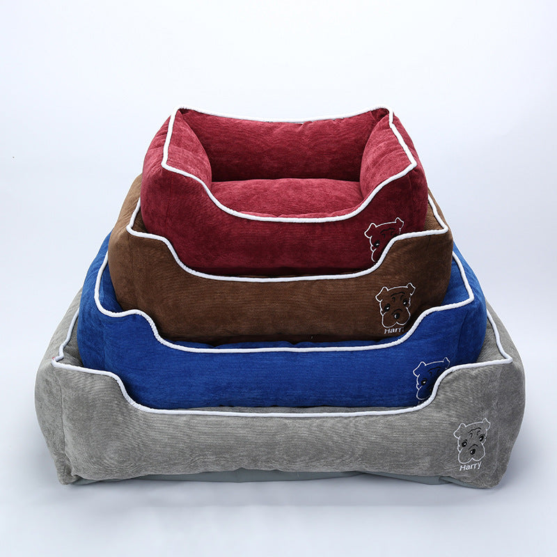 Stacked soft corduroy dog beds in red, brown, blue, and gray with white piping and dog embroidery